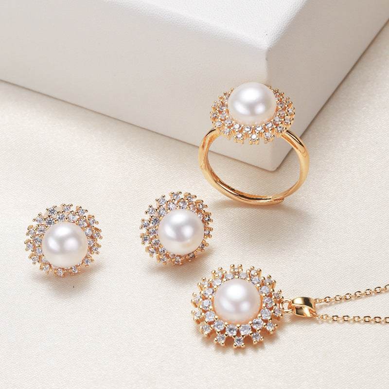 Pearl necklace, ring, and earrings set with gold accents on a light background.