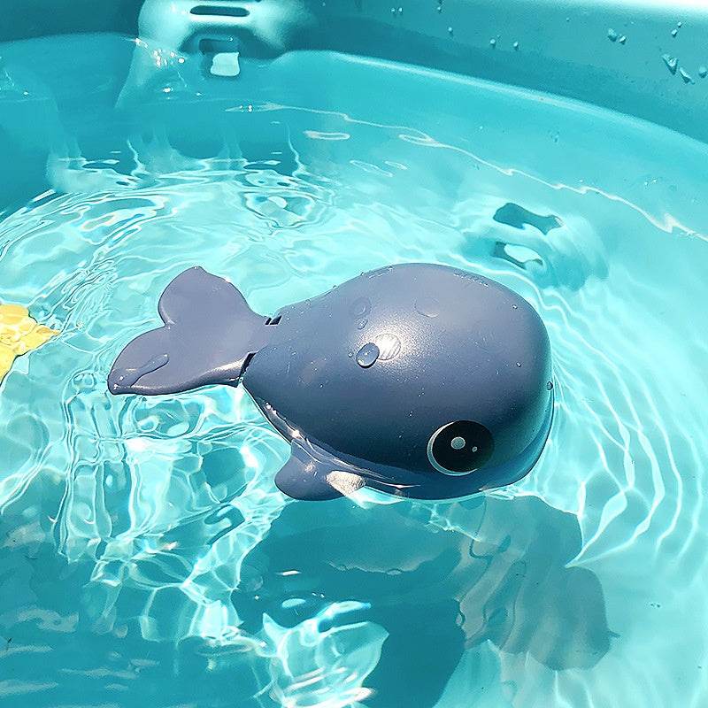 Children's plastic whale bath toy floating in water.