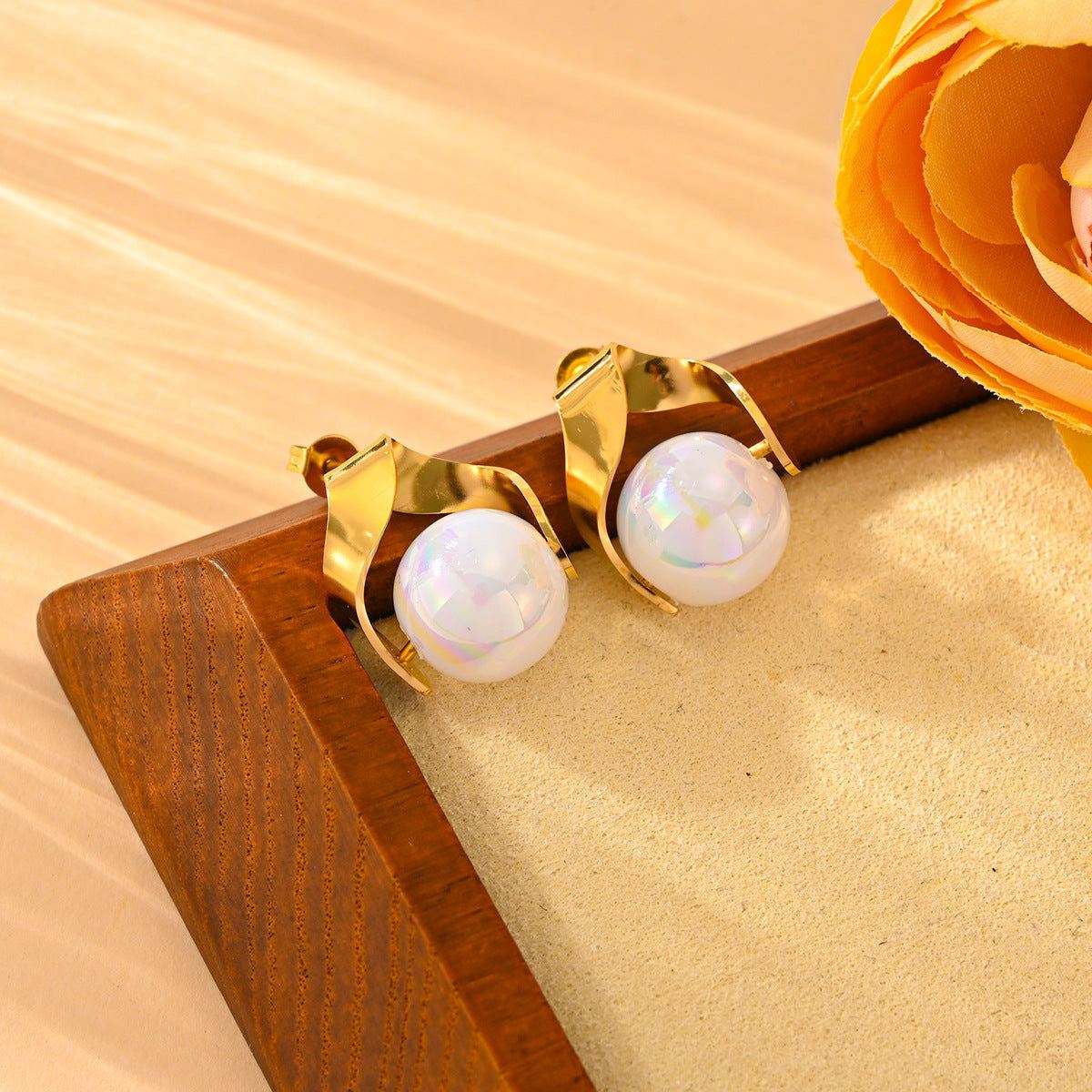 Titanium steel pearl earrings with geometric design on a wooden surface.